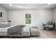 A staged bedroom with a comfortable bed, bench, side table, and a view from the window at 309 N Kepler Rd, Deland, FL 32724