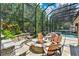 Cozy screened-in patio with a stone fire pit, seating area, and lush garden surroundings at 4052 Gilder Rose Pl, Winter Park, FL 32792