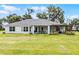 Expansive backyard featuring a covered patio, outdoor kitchen, and lush green lawn at 5478 Nw 153Rd Ct, Morriston, FL 32668