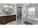 Updated bathroom featuring a round mirror, wooden vanity, and starburst-patterned tile floor at 5478 Nw 153Rd Ct, Morriston, FL 32668