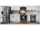 Well-equipped kitchen featuring stainless steel appliances, white cabinets, and stylish stone backsplash at 5478 Nw 153Rd Ct, Morriston, FL 32668