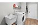 Bright laundry room featuring a utility sink, shelving, and modern white washer and dryer at 5478 Nw 153Rd Ct, Morriston, FL 32668