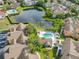 Stunning aerial view of a community with a large pond, colorful buildings, and a sparkling pool surrounded by lush greenery at 8704 Knightsbridge Ct # B, Kissimmee, FL 34747
