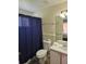Well-lit bathroom featuring a shower with blue curtain, toilet, and sink with vanity at 8704 Knightsbridge Ct # B, Kissimmee, FL 34747