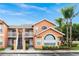 Attractive condo building with orange exterior, white balconies, and lush tropical landscaping at 8704 Knightsbridge Ct # B, Kissimmee, FL 34747