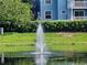 Scenic view of a pond with a fountain, lush greenery, and blue buildings in the background at 8704 Knightsbridge Ct # B, Kissimmee, FL 34747