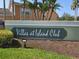 Entrance sign for Villas at Island Club framed by mulch and lawn at 8704 Knightsbridge Ct # B, Kissimmee, FL 34747