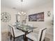 Elegant dining room with glass-top table, chandelier, and city skyline art, perfect for Gathering meals at 8811 Bally Neal Loop, Davenport, FL 33896
