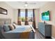 Bedroom with queen bed, blue bedding, multi-toned curtains, a ceiling fan, and a wall-mounted television at 987 Nathan Ridge Rd, Clermont, FL 34715
