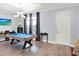 Spacious living area with a pool table, wood floors, modern chandelier, and large window with elegant dark curtains at 987 Nathan Ridge Rd, Clermont, FL 34715