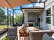 A covered patio with a stainless steel grill, a mounted TV, and lounge seating at 987 Nathan Ridge Rd, Clermont, FL 34715