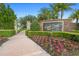 Landscaped entrance to Eagle Creek featuring a brick sign, stone pillars, vibrant flowers, and mature shrubbery at 10430 Belfry Cir, Orlando, FL 32832