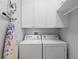 Functional laundry room with washer, dryer, storage cabinets, and an ironing board at 10430 Belfry Cir, Orlando, FL 32832