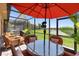 View of the screened in patio with wicker patio furniture, table, and umbrella overlooking the lake at 10430 Belfry Cir, Orlando, FL 32832