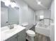 Bright bathroom featuring a gray vanity, toilet, jetted tub with tile surround, and modern fixtures at 1288 Se 32Nd St, Ocala, FL 34471
