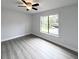Neutral bedroom with wood-look flooring, ceiling fan, neutral walls, and a large window at 1288 Se 32Nd St, Ocala, FL 34471