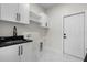 Functional laundry room with white cabinets, black hardware, black granite countertop, and marble floors at 13619 Sw 78Th Place, Dunnellon, FL 34432