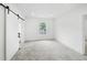 Bedroom with neutral carpet, white walls, barn-style closet door and a view to a bathroom at 161 Bolender Rd, Auburndale, FL 33823