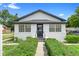 Charming white stucco bungalow featuring black trim, symmetrical windows, and manicured front hedges at 161 Bolender Rd, Auburndale, FL 33823