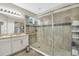 Elegant bathroom featuring double sinks, framed mirror, shower with glass door, and neutral tile at 1821 Benevento St, St Cloud, FL 34771