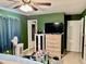 Bedroom with ceiling fan, green walls and a dresser with television at 2 Clear Pl, Ocala, FL 34472