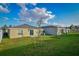 The grassy backyard has a sliding glass door, a patio and young trees at 214 Brave Rd, Davenport, FL 33837