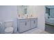 Bathroom featuring double sink vanity with light gray cabinets and white countertops; toilet, mirror and doorway to bedroom at 214 Brave Rd, Davenport, FL 33837