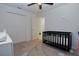 This room features carpeted floors, a ceiling fan, a doorway, a black crib and a large closet at 214 Brave Rd, Davenport, FL 33837
