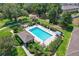 Aerial view of a community pool with a lounge area surrounded by lush greenery at 214 Glasgow Ct, Davenport, FL 33897
