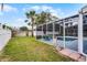 Fenced backyard with a screened-in pool area, palm tree, and green grass at 2203 Essex Dr, Ocoee, FL 34761