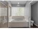 Bathroom featuring a tiled tub under a glass block window and a separate glass door shower at 2203 Essex Dr, Ocoee, FL 34761