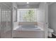 Bathroom featuring a tiled tub under a glass block window and a separate glass door shower at 2203 Essex Dr, Ocoee, FL 34761
