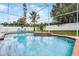 Large screened-in pool with a white fence in the background, lush vegetation, and brick trim around pool at 2203 Essex Dr, Ocoee, FL 34761