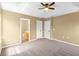 The bedroom has neutral walls, a ceiling fan, and carpeted floor, with a view to the en-suite bathroom at 2488 Hassonite St, Kissimmee, FL 34744