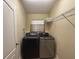 Compact laundry room featuring a modern washer and dryer and overhead shelving at 2585 Woodside Ridge Dr, Apopka, FL 32712