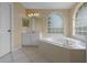 Spacious bathroom with a jacuzzi tub, a tiled surround, vanity, and an arched window for natural light at 2888 Middleton Cir, Kissimmee, FL 34743