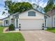 A bright white two-car garage with a blue trim, potted plants on the side, and a well-kept lawn in front at 5729 Norman H Cutson Dr, Orlando, FL 32821