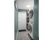 Efficient laundry room with a stacked washer and dryer unit, built-in shelves, and a gray tiled floor at 5729 Norman H Cutson Dr, Orlando, FL 32821