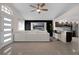 Open-concept living room with a ceiling fan, white sectional sofa, and a view of the sleek, modern kitchen at 5729 Norman H Cutson Dr, Orlando, FL 32821