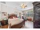 Comfortable bedroom with wood floors, ceiling fan, and cozy reading chair by the window at 7135 Sw 129Th St, Ocala, FL 34473