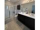 Bright bathroom with double sinks, dark cabinets, a glass-enclosed shower, and tiled floor at 7629 Ripplepointe Way, Windermere, FL 34786