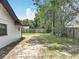 The exterior side of the house, green grass, and a wooden fence in a serene backyard setting at 7679 Bent Bow Trl, Winter Park, FL 32792