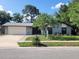 Charming single-story home with stone facade, well-manicured lawn, mature trees, and a paved driveway at 7679 Bent Bow Trl, Winter Park, FL 32792