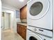 Laundry room with full-size stackable washer and dryer, wood cabinets and granite counter tops at 7679 Bent Bow Trl, Winter Park, FL 32792