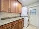 Bright laundry area with stackable washer/dryer and cabinets, granite counters, and backyard access at 7679 Bent Bow Trl, Winter Park, FL 32792