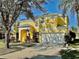 Bright yellow two-story home with a two-car garage and mature landscaping under a clear blue sky at 8520 La Isla Dr, Kissimmee, FL 34747