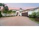 An elegant front exterior view of a property showcasing the well-manicured brick drive and palm trees at 9743 Covent Garden Dr, Orlando, FL 32827