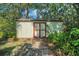Exterior of a small backyard shed with double doors, surrounded by lush greenery and a brick path at 102 Ichabod Trl, Longwood, FL 32750