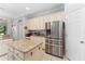 Well-lit kitchen featuring a stainless steel refrigerator, an island with granite countertop and white cabinets at 13108 Lakeshore Grove Dr, Winter Garden, FL 34787