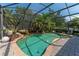 Beautiful screened-in pool with a lush landscape including palm trees and stone features at 13108 Lakeshore Grove Dr, Winter Garden, FL 34787